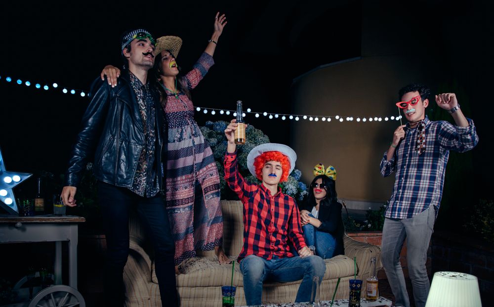 Happy friends having fun with costumes at party