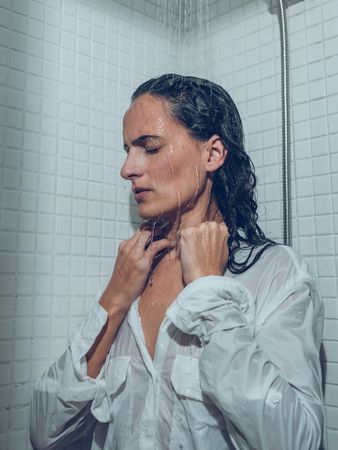 Tired woman with wet hair in shirt taking shower