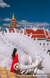 Woman wearing red dress standing beside light dragon statue at the exterior of Wat Huay Pla Kang temple in Thailand 4Zwlrb