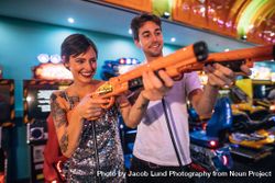 Man and woman playing shooting games with gaming guns at a gaming arcade 47Oj64