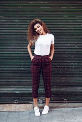 Smiling Arab woman with curly hair standing outside of metal security doors