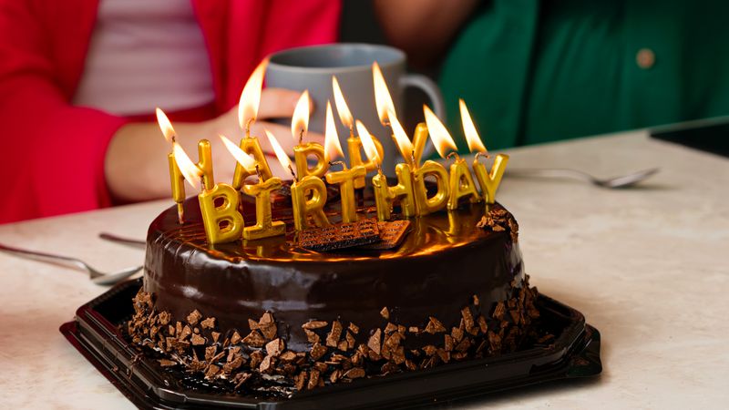 Birthday cake with lit candles and chocolate shards