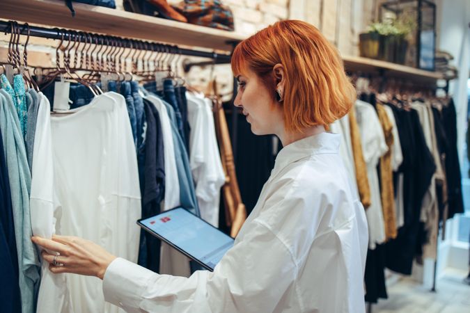 Woman taking inventory on digital tablet in clothing store