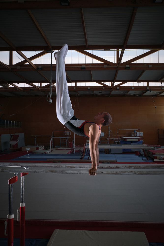 Young male gymnast doing exercises on the parallel apparatus.