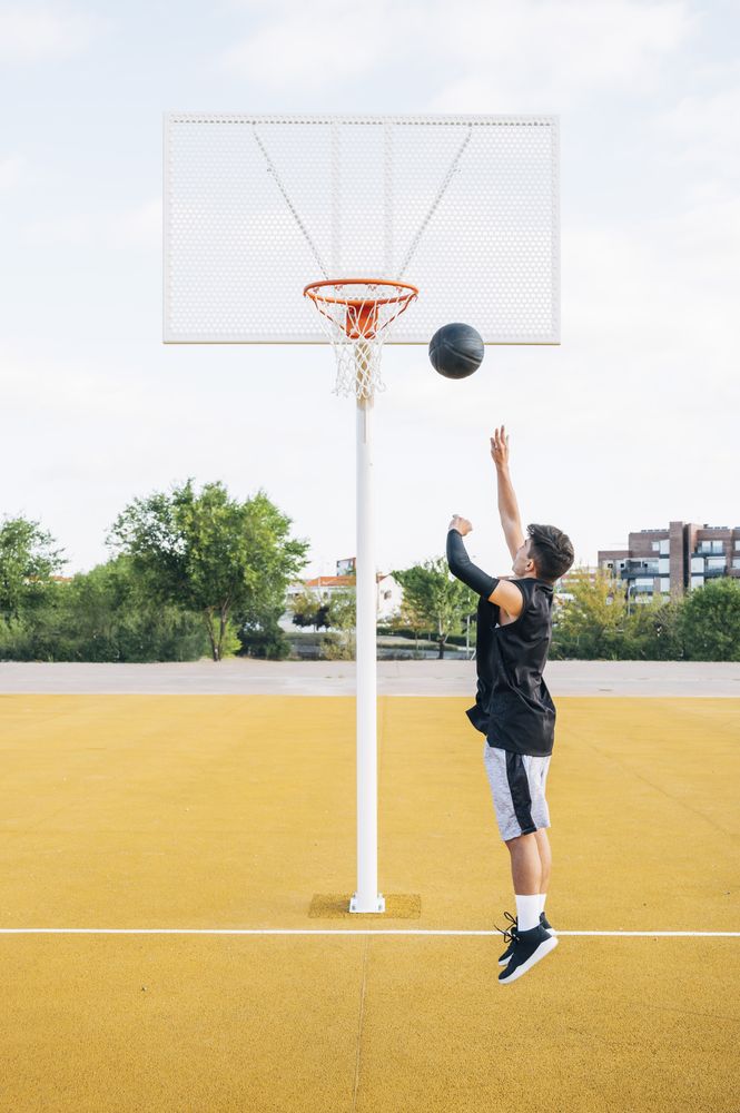 Young man playing on basketball court outdoor.