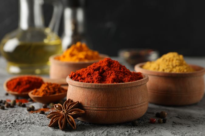 Side view of bowls of spices and garlic bulb, with cooking oil