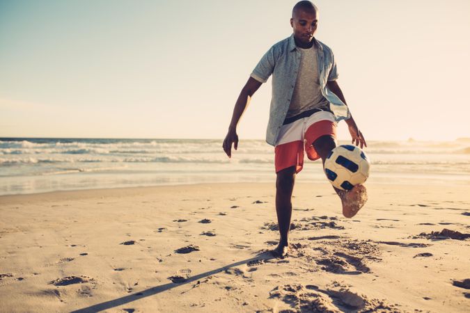 Young man playing soccer at the seaside