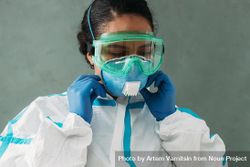 Female doctor in PPE gear and medical hazmat suit adjusting her mask bEA7Vb