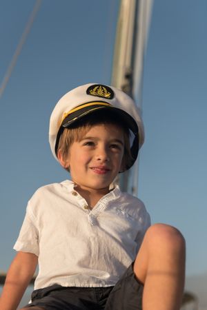 Smiling child sitting on deck of yacht in sea