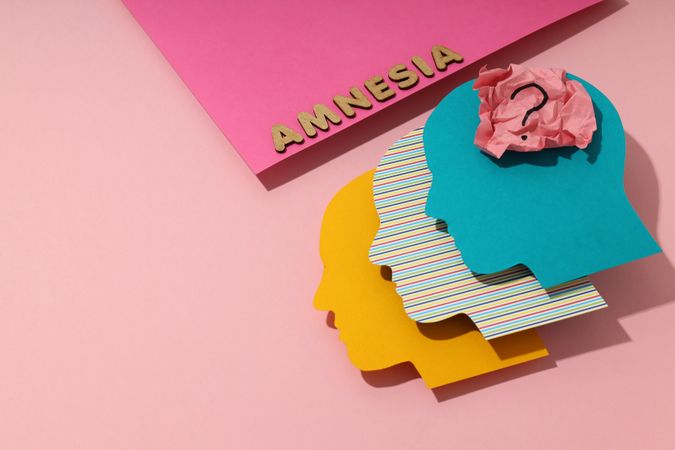 Colorful head shaped heads on pink background with the word “Amnesia” with copy space