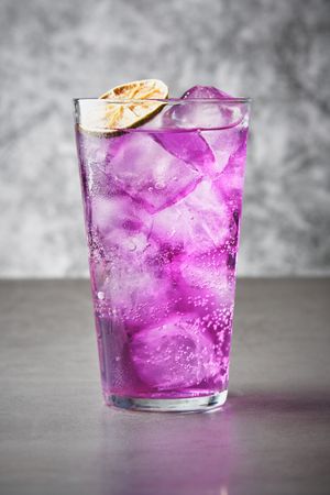 Refreshing drink with purple ice with dehydrated orange slice