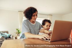 Woman with baby using laptop, working from home 4APVE5