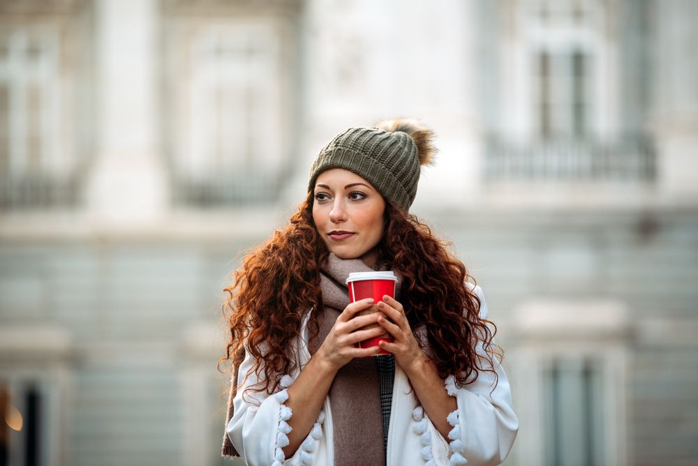 Woman drinking coffee wandering in the streets of Madrid on winter