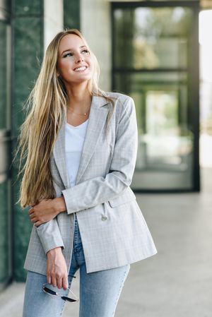 Smiling woman in blazer looking up outside of building