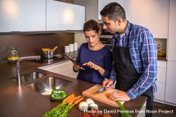Couple checking digital tablet while prepping vegetables for dinner 5wOaW5