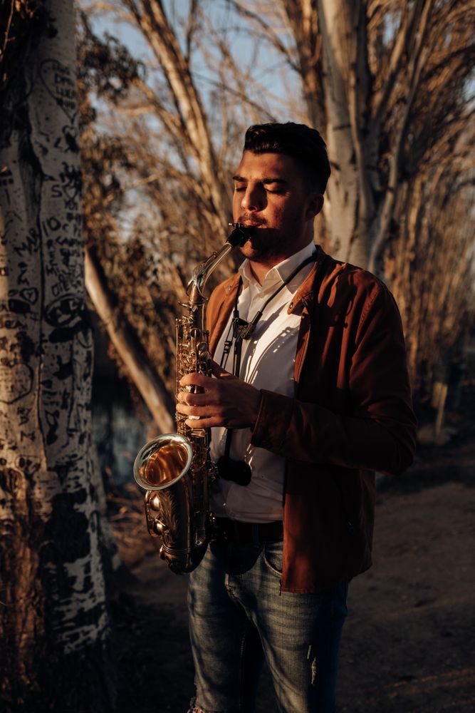 young musician playing the saxophone at sunset