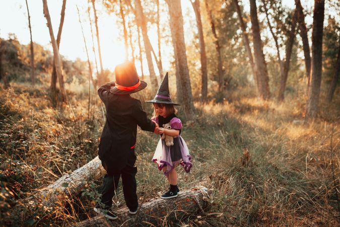 Brother and sister playing in the forest dressed in halloween costumes