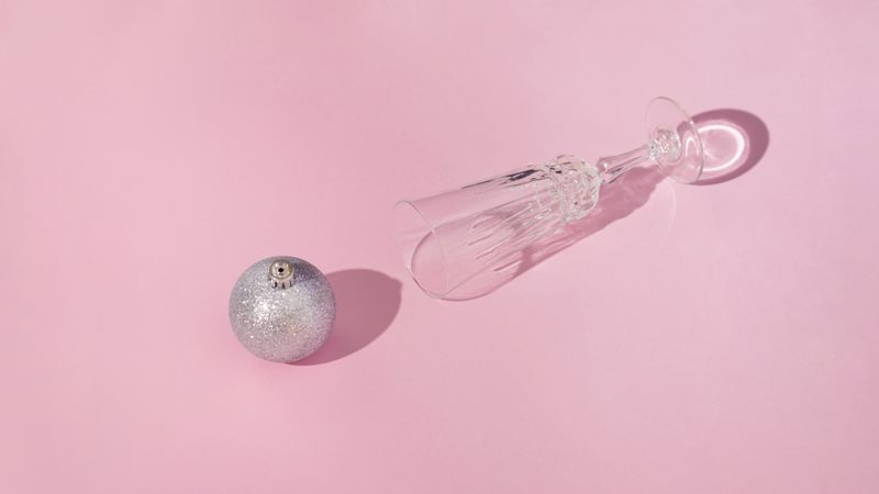 Champagne flute lying on it’s side with silver xmas bauble
