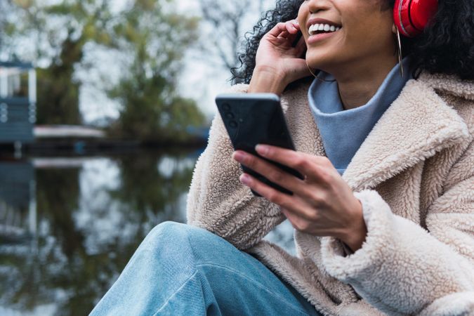 Cheerful Black woman listening to music in park
