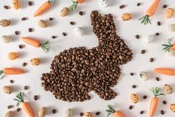 Coffee beans in bunny shape with decorative eggs and carrots