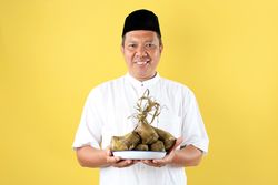 Mature Asian Man Holding A Plat eof Ketupat Rice Cake for Lebaran Ied Al Fitr