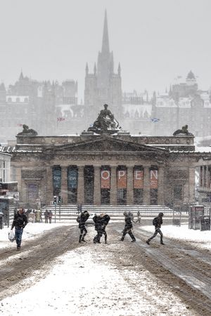 People walking on street near building in Edinburgh University campus while snowing