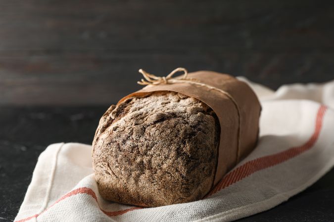 Rye bread on kitchen towel on table against wooden background, space for text and closeup