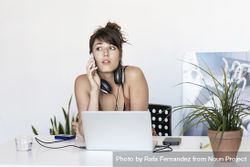 Female listening to message on smartphone at home office 0Vnz30