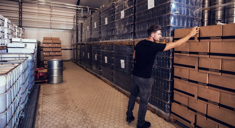 Young businessman looking at packaged beer boxes in warehouse