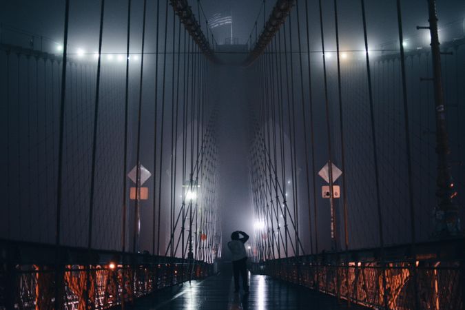 Person standing in the middle of concrete bridge during nighttime