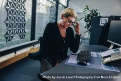 Mature businesswoman looking tired sitting at her desk 5Xnx7b
