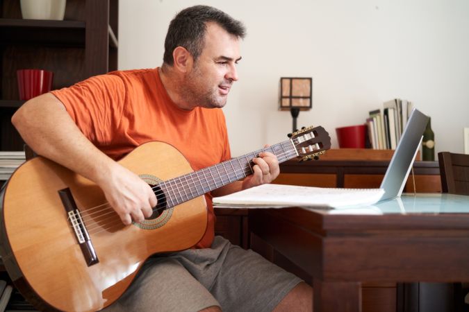 a man with laptop computer in online guitar lessons learning chords