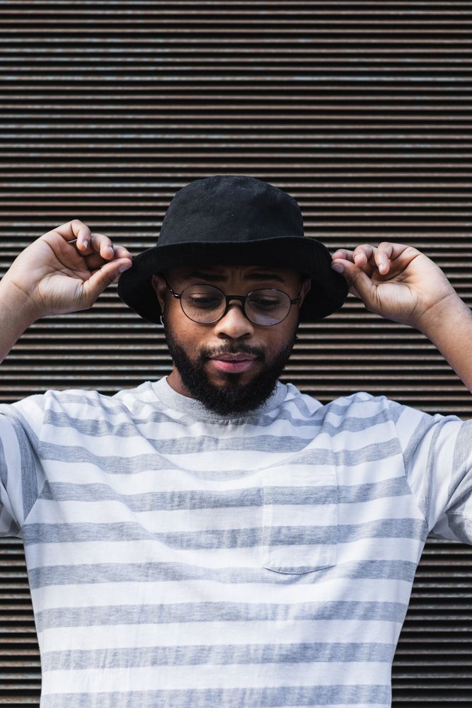Black hipster man in hat looking down