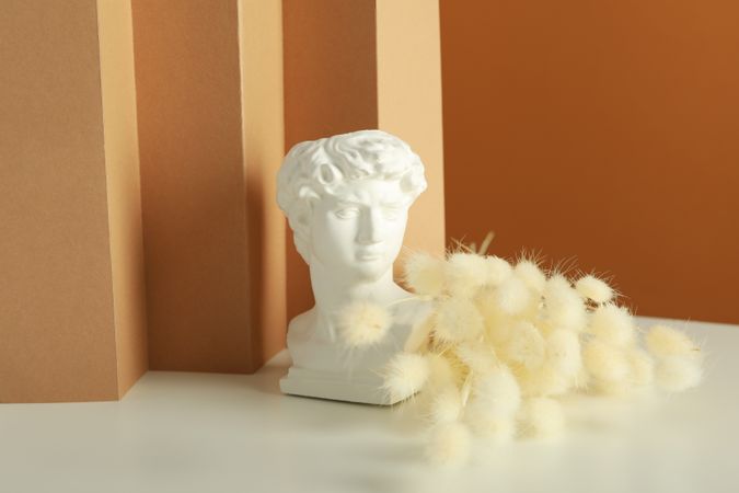 Bust on table with dried flowers in brown room