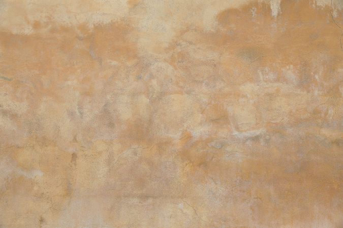 Old rough yellow ochre colored cracked painted plaster wall texture