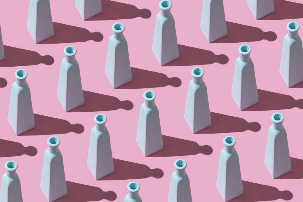 Top view of painted glass bottles on pink background