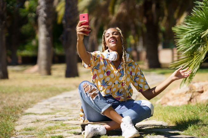 Smiling female in bold patterned shirt taking selfie in park