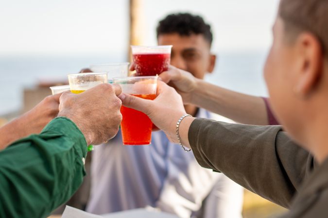 Young friends celebrating with colorful drinks by the seaside