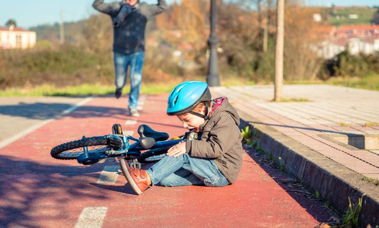 Boy in helmet crying after falling off his bike
