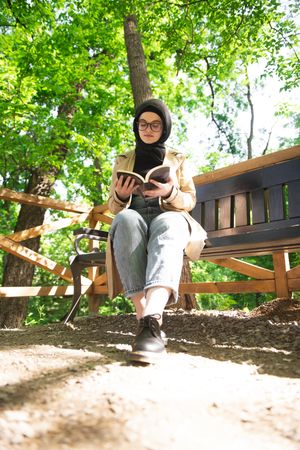 Female in headscarf reading under a tree