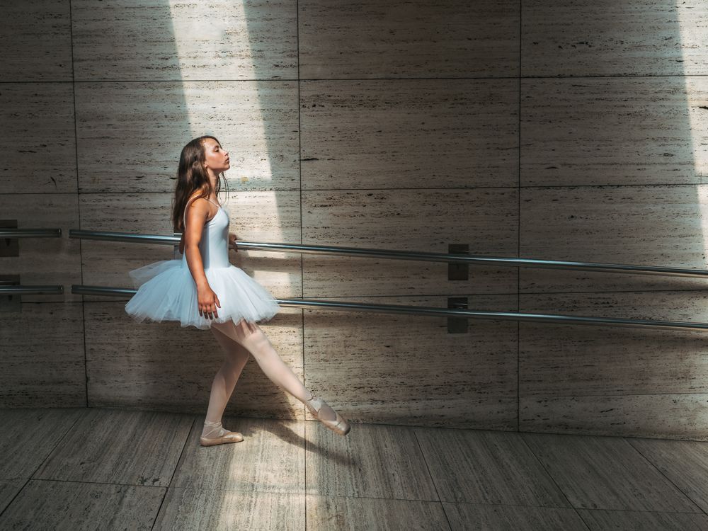 Ballerina doing ballet posing at rail in classroom
