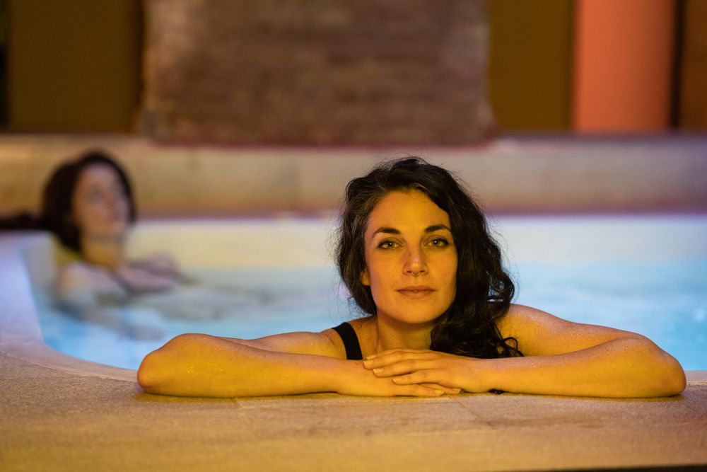 Woman coming up from side of bath in spa