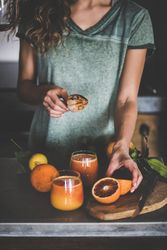 Woman holding squeezer with freshly squeezed blood orange juice