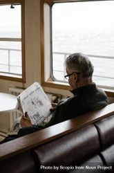 Back view of older man in brown sweater reading newspaper 476ga5