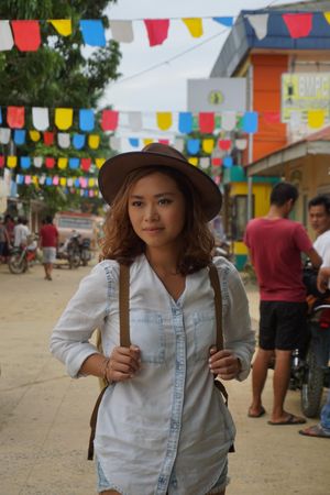 Woman wearing a hat standing on street