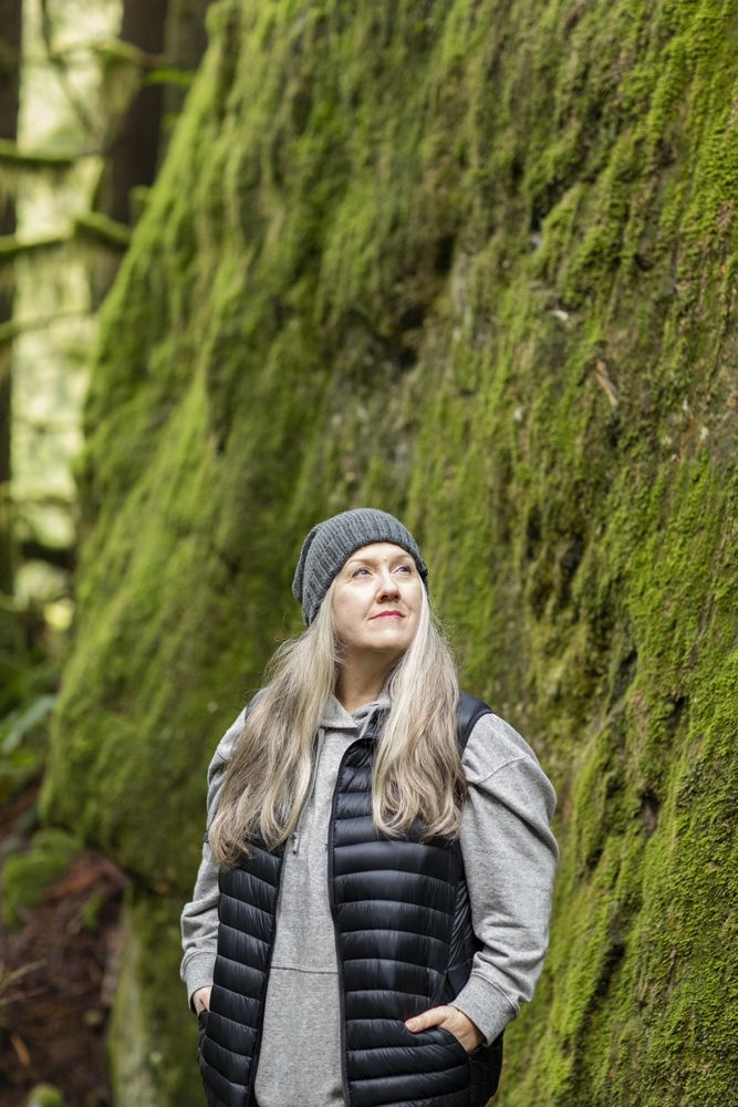 Contemplative woman looking up while posing in front of mossy rock wall