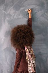 Black girl writing on chalkboard in classroom