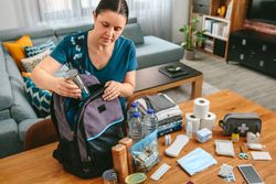 Woman putting cans of food to prepare emergency backpack
