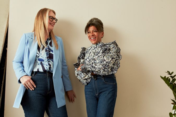 Two older woman in professional clothing smiling in studio together