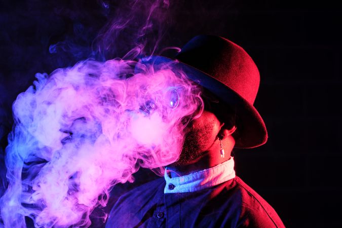Stylish man with smoke in neon